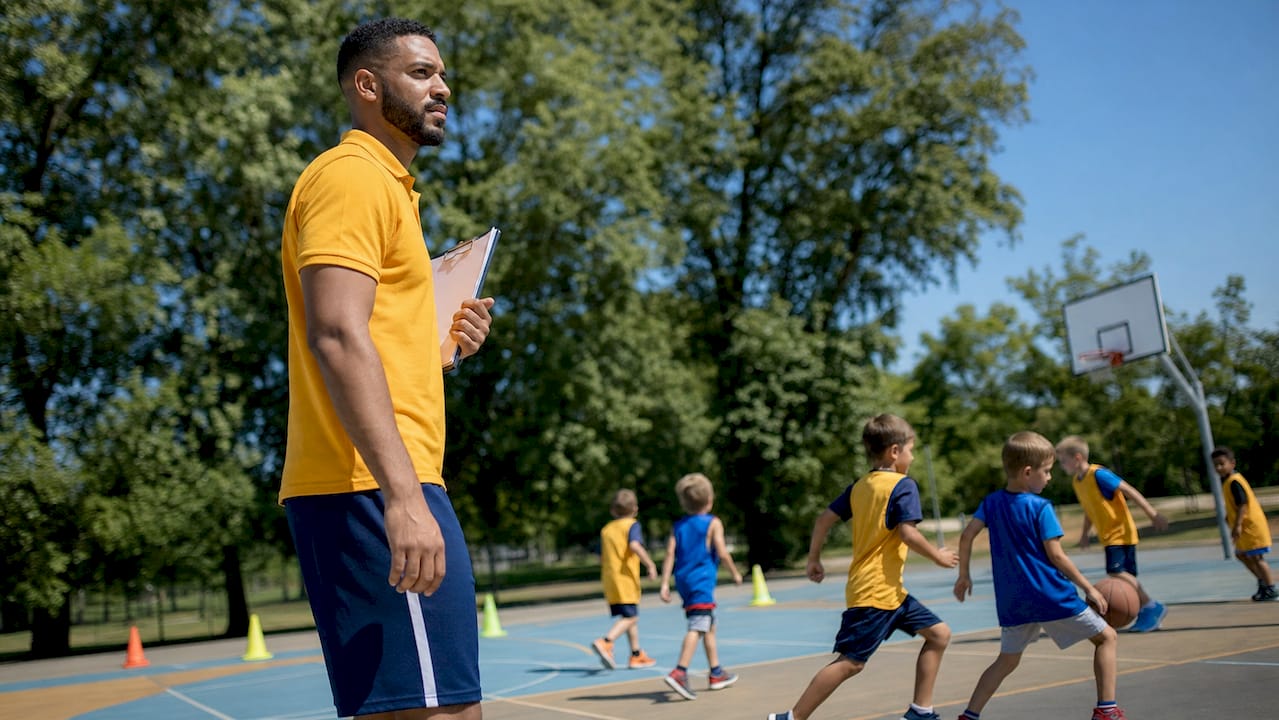 Youth basketball coach observing mini-game drills